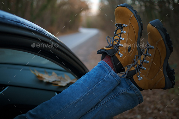 Woman feet on car door. Feet outside the window at sunset forest