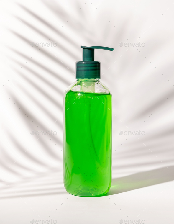Cosmetic pump dispenser bottle filled with green liquid on white, Palm leaf hard shadows