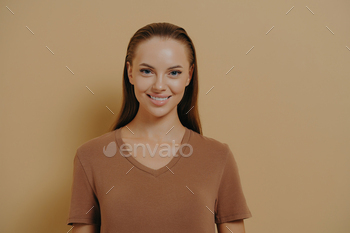 Natural beauty. Young charming woman with daily makeup wearing basic beige t-shirt smiling at camera