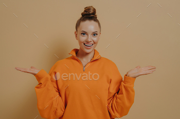 Studio shot of young happy woman spreading arms in excitement, emotionally reacting to news