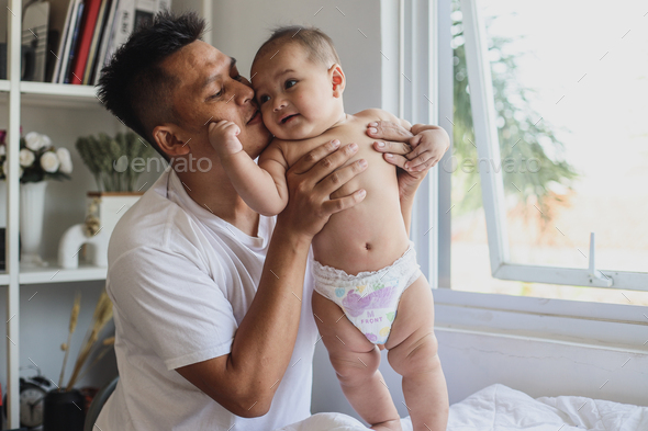 Father kissing adorable boy at home