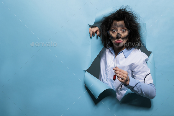 Crazy looking scientist with goofy face and messy hair holding glass test tube filled with