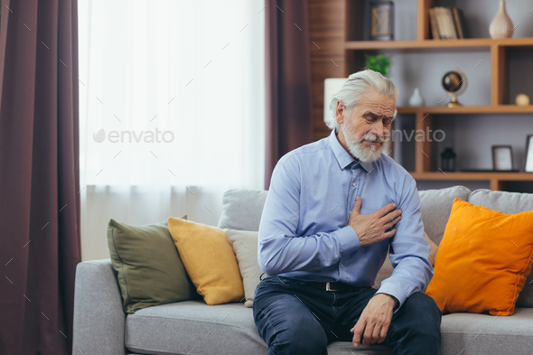 The older man sits at home alone, the grandfather holds his hands on his chest, his heart aches