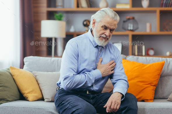 The older man sits at home alone, the grandfather holds his hands on his chest, his heart aches
