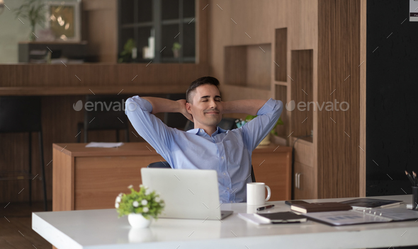 Relaxed calm caucasian businessman resting sit at office desk after working for financial with