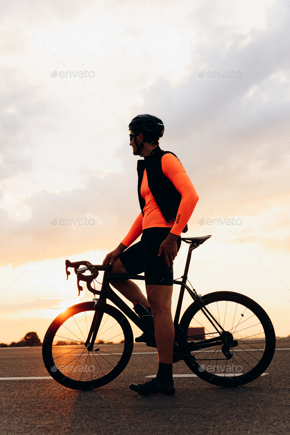 Athletic man sitting on bike and enjoying sunset