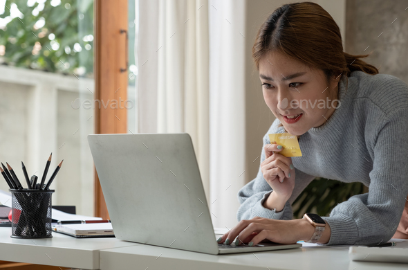 Close up image of a happy woman holding credit card while using laptop computer. online shopping