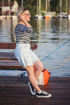 Attractive woman posing on the marina at a sunny summer day