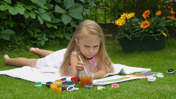 Blond girl paints on the grass