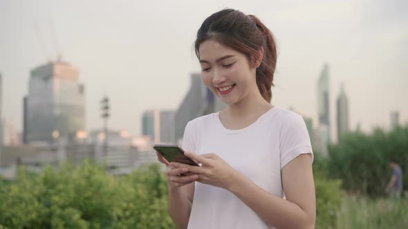 Asian tourist blogger woman using touchscreen technology at smartphone while walking. alt