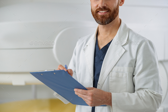 Close up of Radiologist making notes on clipboard on backgraund of MRI or CT or PET Scan