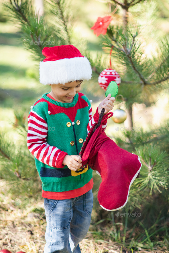 Little boy in sweater and hat waiting for a Christmas in the wood Stock Photo by serenkonata