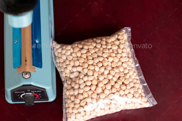 Bag of chickpeas sealed next to the sealer. Plastic film sealer. Concept of manual and simple works.