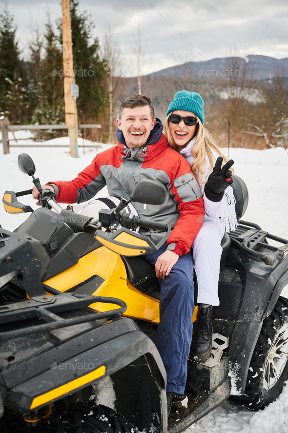 Portrait of happy man and woman posing on offroad four-wheeler ATV.
