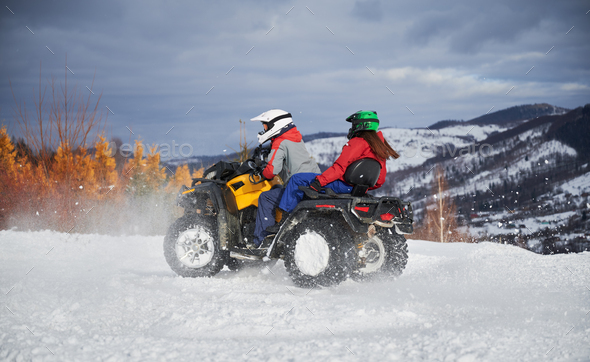 Portrait of man and woman riding on offroad four-wheeler ATV.