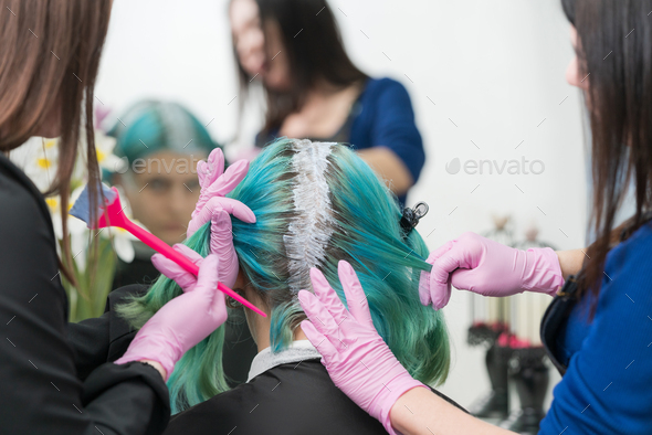 Process hair dye in beauty salon. Two hairdressers apply paint to hair during bleaching hair roots