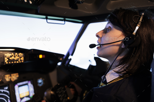 Female copilot flying plane from cockpit with dashboard command