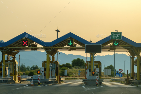 Paid expressway checkpoint tollgate by hills at back sunset - Stock Photo - Images