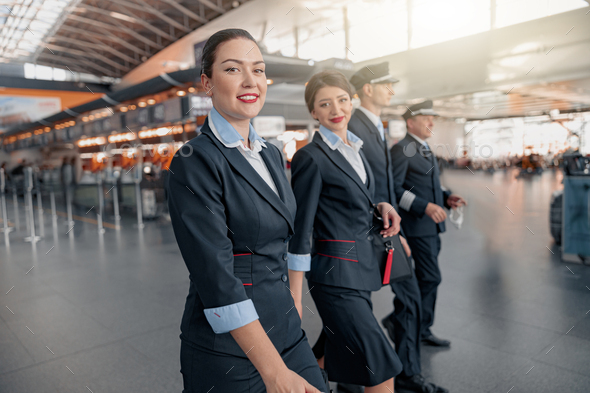 Two flight attendants and pilots walking through the terminal to the ...