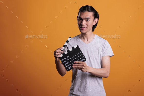 Asian cameraman assistant slapping film making clapperboard