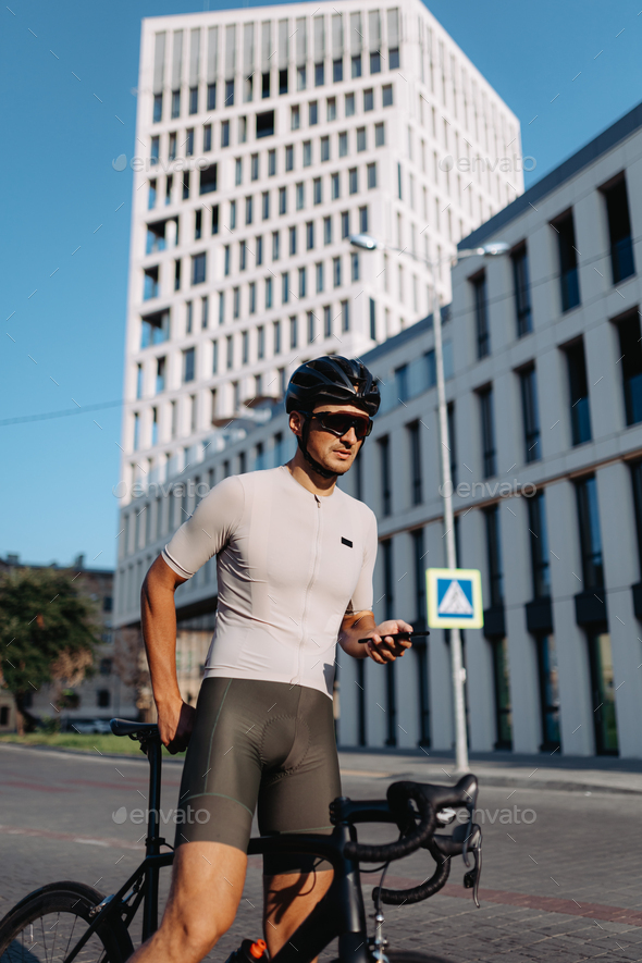 Sporty man resting on bike outdoors and using mobile - Stock Photo - Images
