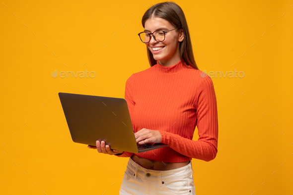 Portrait of intelligent woman teacher having lesson online on laptop, isolated on yellow background