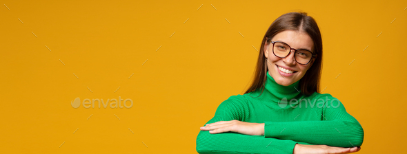 Happy woman with folded hands listening to teacher isolated on yellow background with copy space