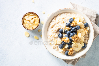Oatmeal porrige in craft bowl at white background.