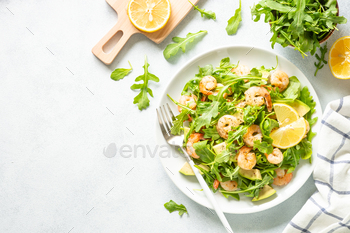 Shrimp salad with arugula and avocado at white.