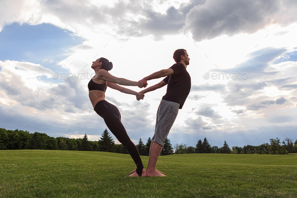 Young healthy couple doing acro yoga in the sunny summer park. Fitness ...