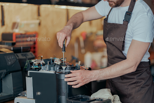 Close up of man hands repairing coffee machine in a workshop