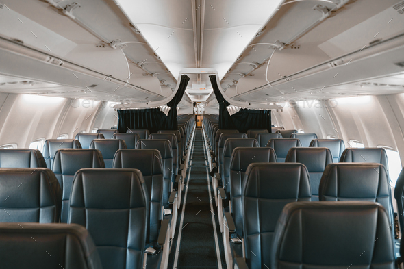 Commercial aircraft cabin with rows of seats down the aisle