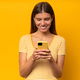 Woman using app on phone, looking at screen with joy, isolated on yellow background - PhotoDune Item for Sale