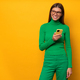 Portrait of smiling woman in glasses standing on yellow background with phone looking on copy space - PhotoDune Item for Sale