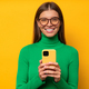 Portrait of woman with phone on yellow copy space background browsing dating app - PhotoDune Item for Sale