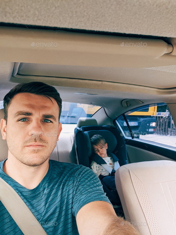 Dad driving a car with a small child in a child seat behind