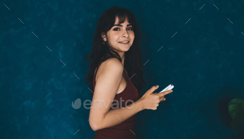 Portrait of gorgeous smiling woman standing with mobile phone on copy space background.
