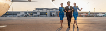 Full length shot of excited male pilot walking together with two female flight attendants in blue