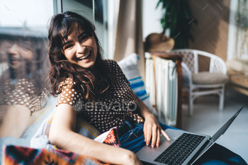 Happy female freelancer browsing network while working distantly and shopping online with netbook