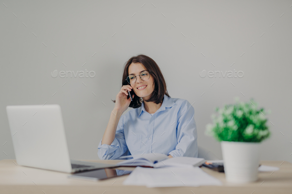 female recruiter makes job offer to somene via cell phone, checks curriculum vitae on laptop - Stock Photo - Images