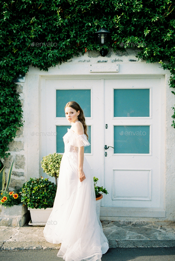 Bride stands in front of the entrance to the building overgrown with ivy