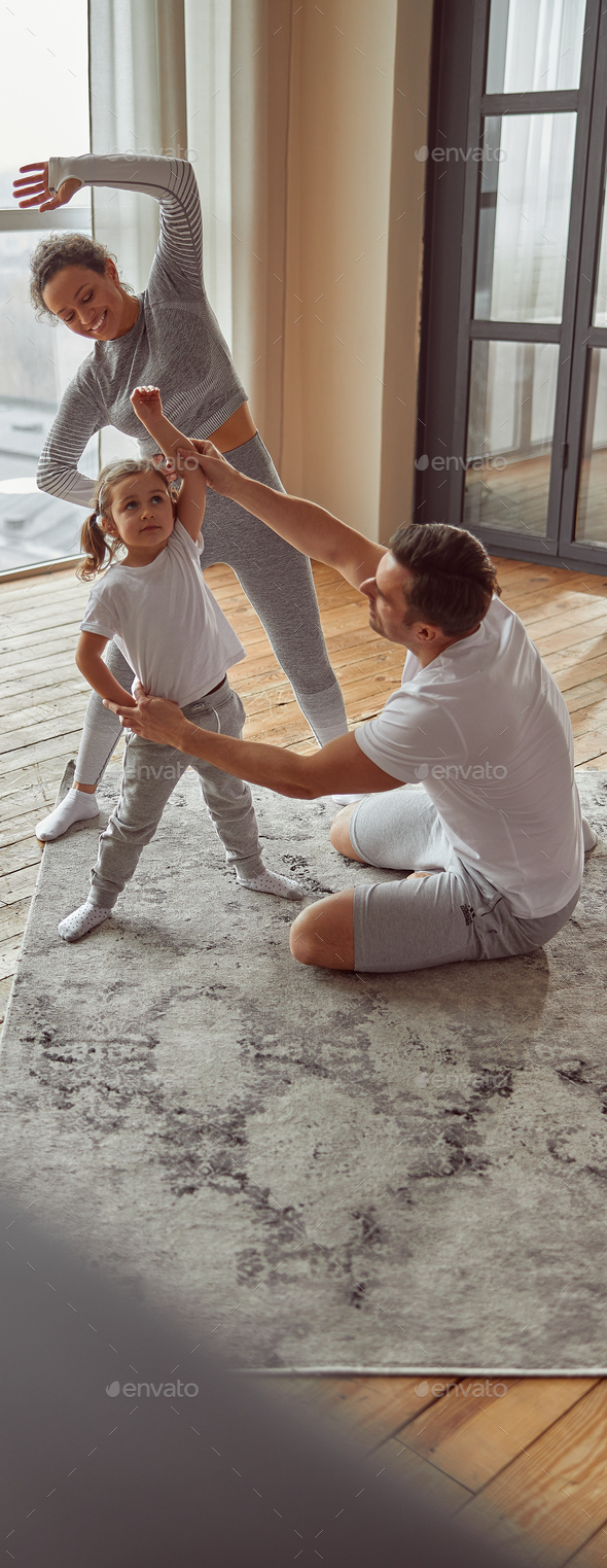 Jolly sporty family doing gymnastics together indoors