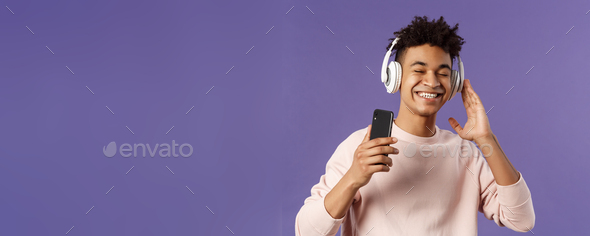 Technology and lifestyle concept. Portrait of carefree attractive young man enjoying fine sound