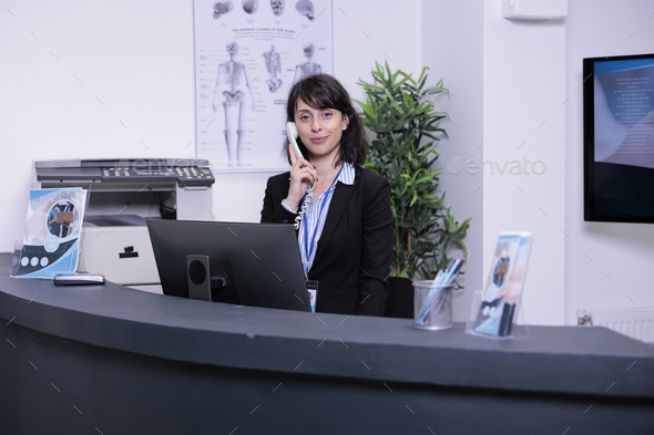 Portrait of smiling hospital receptionist answering call from patient to make an appointment for