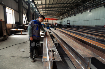 Worker measuring steel bar with measuring tape