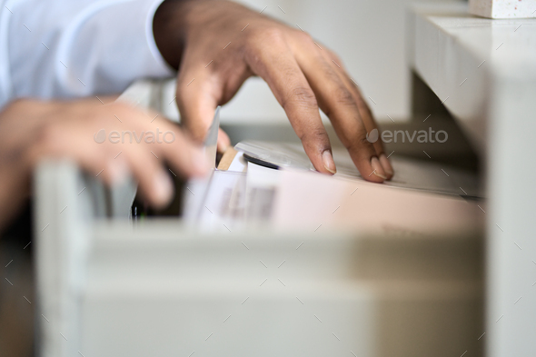 Male hands searching corporate documents files in archive drawer.