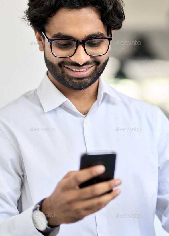 Happy young indian business man using smartphone at work in office ...