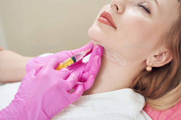 Elegant Caucasian female is getting injection for smoothing of neck wrinkles