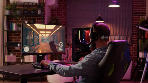 Man using pc gaming setup relaxing playing multiplayer online action game talking to team on headset