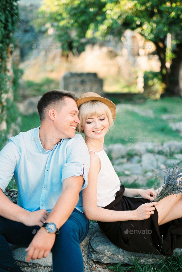 Smiling couple sitting on stone steps in the garden - Stock Photo - Images